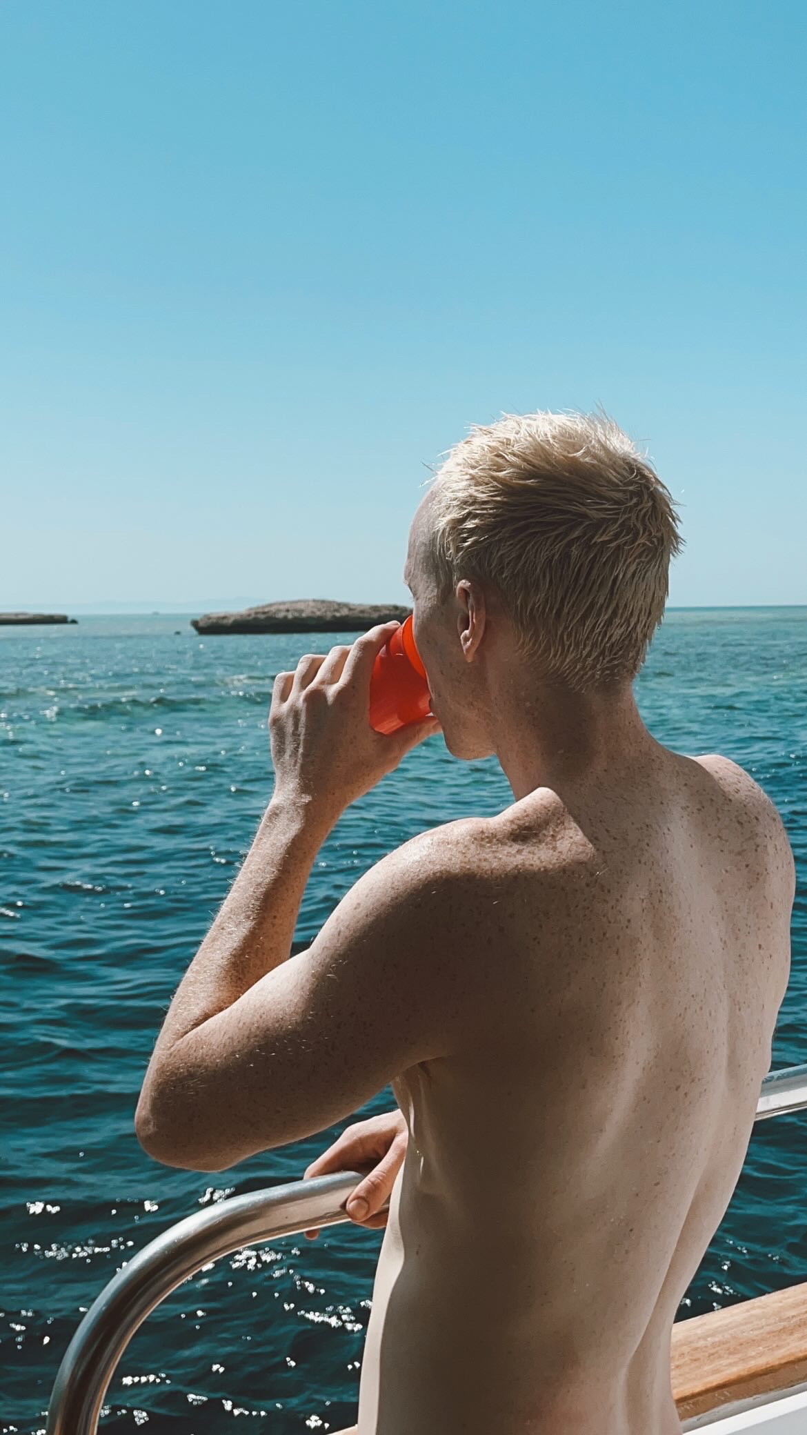 Figure seen from behind beside bright blue water