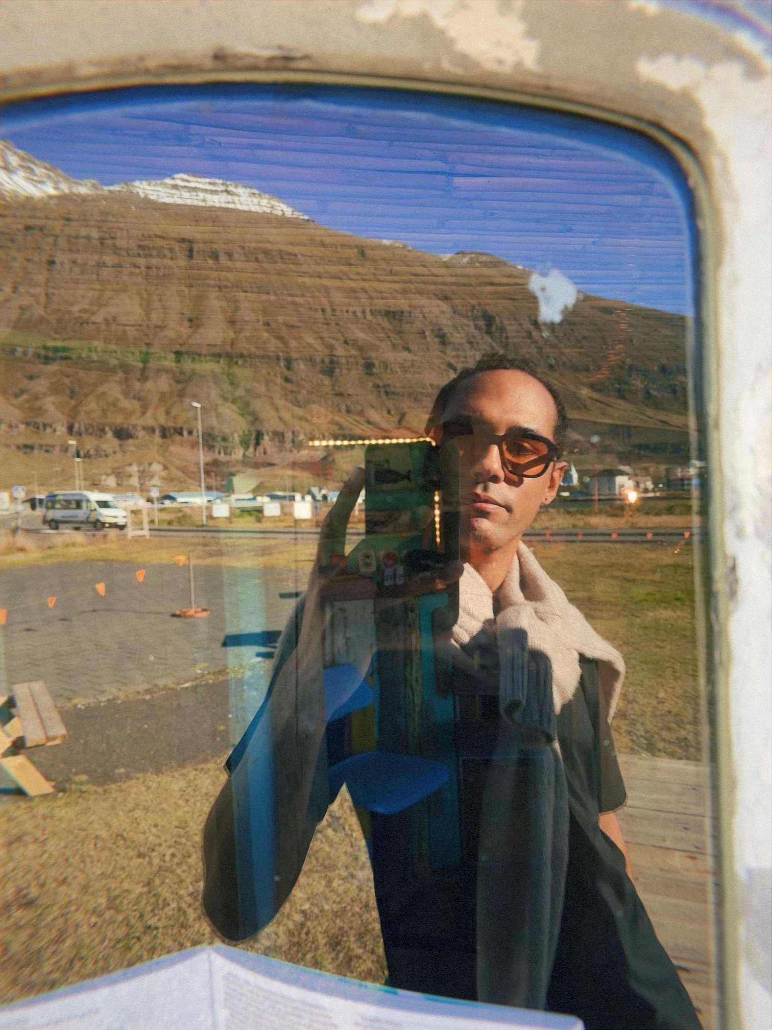 Portrait reflected in a window against an earthy landscape